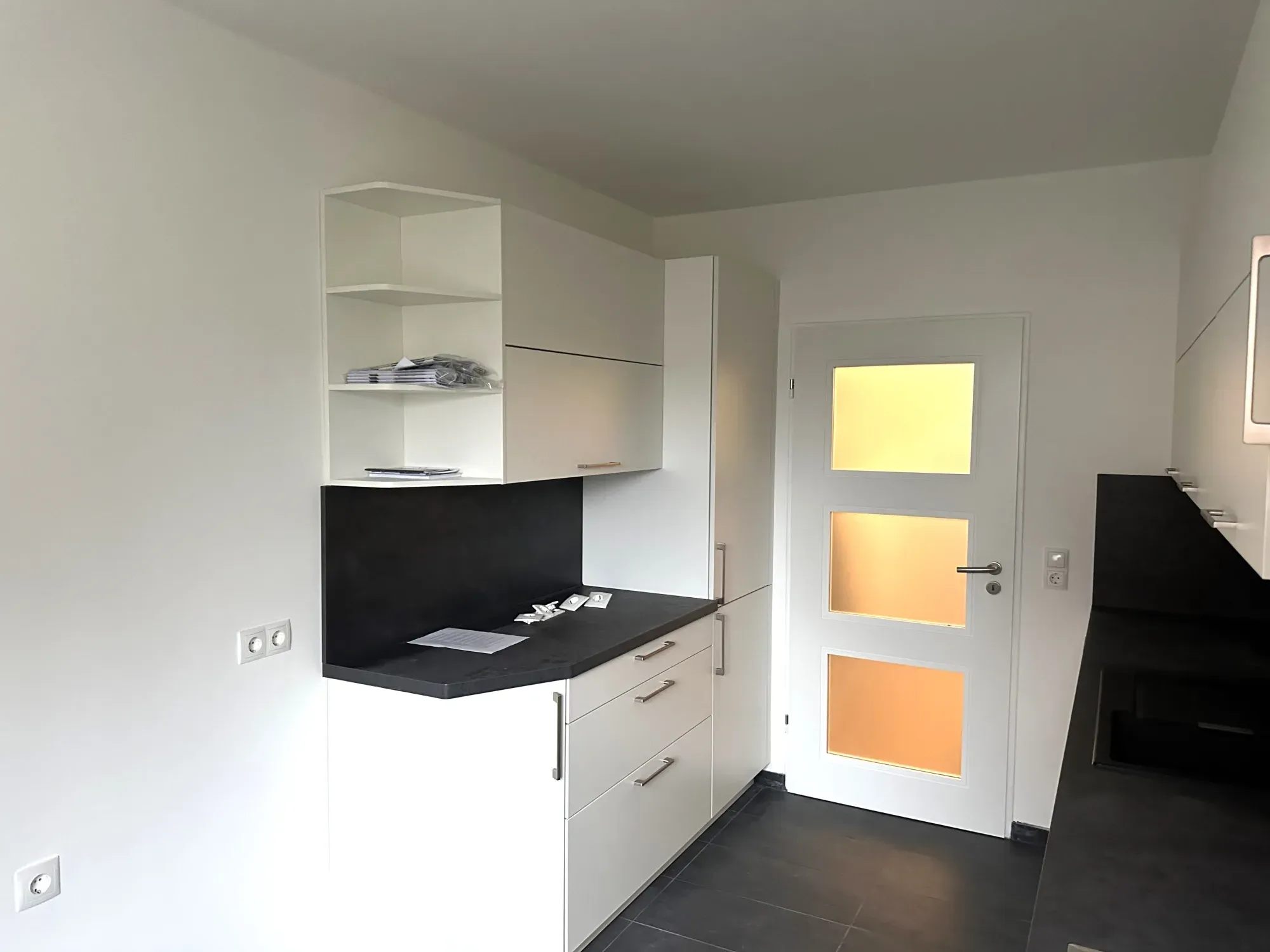 Küchenecke mit Oberschränken, Eckregal und Glaseinsatztür zum Flur